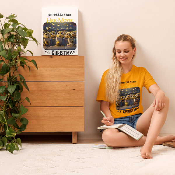 Smiling woman sitting against a wall wearing Bee Movie Christmas T-shirt.